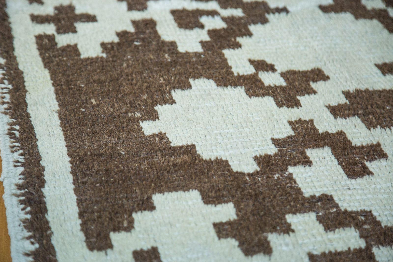 Rich texture of wool pile, featuring geometric pale ivory and deep brown pattern.